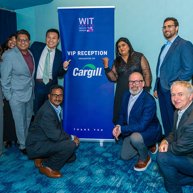 Ten people pose and smile around a blue WIT VIP Reception presented by Cargill banner at an indoor event. They are dressed in business or business-casual attire.
